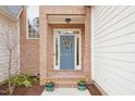 Close up of a blue front door surrounded by brick, potted flowers, and a decorative wreath at 104 Barnes Spring Ct, Cary, NC 27519