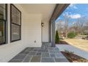 Charming covered porch with bluestone tile flooring, gray columns, and stylish exterior lighting fixture at 109 W Markham Ave, Durham, NC 27701
