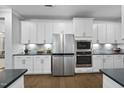Modern kitchen featuring stainless steel appliances, white cabinets, and stylish backsplash at 131 English Violet Ln, Raleigh, NC 27610