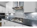 Gourmet kitchen with stainless steel range hood and cooktop with marble backsplash at 131 English Violet Ln, Raleigh, NC 27610