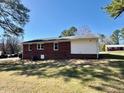 View of the backyard of a brick home with an open grass area at 1723 Lynne Ave, Henderson, NC 27536