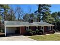 Classic red brick ranch-style home with mature trees, a carport, and neat landscaping enhances curb appeal at 1723 Lynne Ave, Henderson, NC 27536