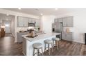 Modern kitchen features gray cabinets, stainless steel appliances, and granite countertops with seating at 20 Granite Falls Way, Youngsville, NC 27596
