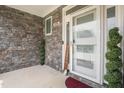 Close-up of front door with glass accents, stylish stone wall, and manicured shrubs at 206 Hamby St, Clayton, NC 27520