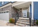 A welcoming front porch with stone stairs and iron railings leading to a front door with stone and siding at 206 Hamby St, Clayton, NC 27520