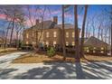 View of the home's brick exterior, multiple windows, and mature trees in a wooded setting at 2602 Vintage Hill Ct, Durham, NC 27712