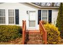 Close up of charming front entrance with steps and wooden railings and shutters at 383 Hardy Rd, Wendell, NC 27591