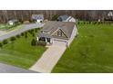 Aerial view of a well-maintained home with a long driveway and large lawn in a wooded neighborhood at 420 Carsons Creek Trl, Wendell, NC 27591