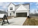 Two-story home featuring light gray siding, attached garage, and a neatly landscaped yard on a bright, sunny day at 44 Rolling Banks Dr, Louisburg, NC 27549