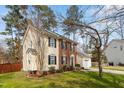 Two-story home featuring brick and yellow siding, surrounded by a lush lawn and mature trees at 6524 Caverstone Dr, Durham, NC 27713