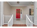 A welcoming front door with a wreath and a 'hello' mat, framed by white railings and brick steps at 7 Dardanelle Ln, Durham, NC 27713