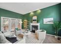 A stylish living room with green walls, a fireplace, and French doors leading to the outside at 7 Dardanelle Ln, Durham, NC 27713