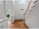 Bright foyer with hardwood floors, white columns, a staircase and a large window, creating a grand entrance at 725 Littleleaf Ct, Holly Springs, NC 27540