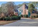 A beautifully landscaped home exterior with a brick chimney and winding driveway, surrounded by mature trees at 725 Thompson Rd, Garner, NC 27529