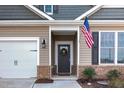 Close-up of a home's front door, showcasing the wreath, American flag, and a glimpse of the attached two-car garage at 10 Parker Pond Ct, Durham, NC 27703
