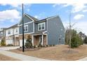 Side view of a modern townhome with blue siding and a well-manicured lawn on a sunny day at 1000 Pyrenees Way, Cary, NC 27519