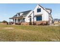 Charming white farmhouse with a covered front porch, black window frames, and professionally landscaped grounds at 107 Crescent Hill Ln, Rougemont, NC 27572