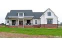 Attractive two-story farmhouse with a covered front porch and brick foundation, complemented by black window frames and a welcoming double-door entry at 107 Crescent Hill Ln, Rougemont, NC 27572