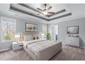 Cozy main bedroom features a tray ceiling, neutral decor, carpet flooring and bright windows at 127 Landfall Ln, Smithfield, NC 27577