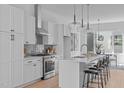 Modern white kitchen with stainless steel appliances, island with seating, and stylish pendant lights at 2002 Moody Ln, Durham, NC 27701