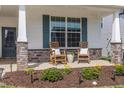 Inviting front porch with rocking chairs, stone accents, and beautiful landscaping create a warm and welcoming entrance at 2059 Dowell Ct, Burlington, NC 27215
