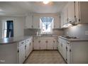 Bright kitchen featuring white cabinetry, countertop bar and large window at 2404 Pearces Rd, Zebulon, NC 27597