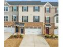 View of townhome exteriors featuring brick accents, garage doors, and colorful front doors with decorative wreaths at 368 Amber Acorn Ave, Raleigh, NC 27603