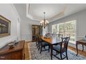 Formal dining room boasts a tray ceiling, wainscoting, and a large window, perfect for gatherings at 5714 Belmont Valley Ct, Raleigh, NC 27612