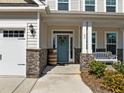 Inviting front porch with stone pillars, a bench, stylish decor and an entry door with a decorative wreath at 63 Capewood Ct, Garner, NC 27529