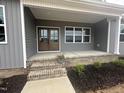 Inviting front porch features a double-door entryway, brick steps, and stylish, neutral-toned siding at 9235 Bear Run Ln, Middlesex, NC 27557