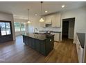 Modern kitchen with dark island, light countertops and cabinets, pendant lighting and hardwood floors at 9235 Bear Run Ln, Middlesex, NC 27557
