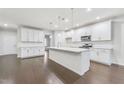 Spacious, modern kitchen with white cabinetry, a large island with seating, stainless steel appliances, and dark hardwood floors at 1103 Freestone Rd, Durham, NC 27703