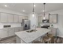Stylish kitchen with stainless steel appliances, granite countertops, an island sink, and gray wood flooring at 1113 Freestone Rd, Durham, NC 27703