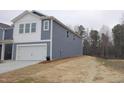 Side angle of a charming two-story home featuring blue siding and a two-car garage at 1120 Solace Way, Rolesville, NC 27571