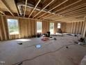 Spacious living room under construction with exposed framing and multiple windows, showcasing the natural light at 33 W Emily Gardens Dr, Selma, NC 27576