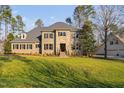 Charming two-story stone and brick home with an expansive lawn, mature trees, and classic black shutters at 3905 Grandbridge Dr, Apex, NC 27539
