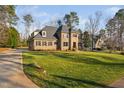 Sprawling brick and stone home with a lush front lawn, a long driveway, and mature trees at 3905 Grandbridge Dr, Apex, NC 27539