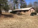 A single story brick home on a large lot with mature trees and a detached garage or shed at 4032 Chaucer Dr, Durham, NC 27705