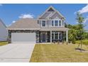 Inviting two-story home with stone accents, a well-manicured lawn, and a two-car garage at 580 Winding Creek Dr, Lillington, NC 27546