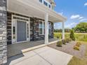 Charming front porch with stone accents and white pillars, creating a welcoming entrance to the home at 580 Winding Creek Dr, Lillington, NC 27546