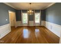 Elegant dining room featuring hardwood floors, wainscoting, and a chandelier, bathed in natural light at 7721 Sutcliffe Dr, Raleigh, NC 27613