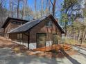 Exterior view of the home displaying its wooden siding, black roof, and surrounding natural landscape at 1269 Manns Chapel Rd, Pittsboro, NC 27312