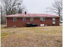 Back of the brick house with a red roof, several windows, and oil drums in the backyard at 16 Marsh Mciver Rd, Bear Creek, NC 27207