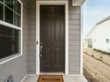 A brown front door with white trim, a 'Welcome' mat, and gray siding, offering a warm invitation at 177 Magenta Rose Dr, Raleigh, NC 27610