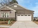 Close up view of the garage featuring stone accents and a paved driveway leading to a charming single-Gathering home at 177 Magenta Rose Dr, Raleigh, NC 27610