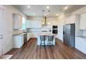 A bright, open kitchen with stainless steel appliances, a center island with seating, and wooden floors at 208 Acorn Crossing Rd, Holly Springs, NC 27540