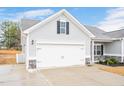 Spacious two-car garage with carriage door hardware, contrasting stone base, and adjacent landscaping at 295 Barbour Farm Ln, Four Oaks, NC 27524
