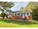 Charming brick home with blue shutters, complemented by a well-maintained front yard and lush greenery at 300 Grove St, Oxford, NC 27565