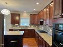 Well-equipped kitchen with granite countertops, stainless steel appliances, and dark wood cabinetry at 3032 Kilarney Ridge Loop, Cary, NC 27511
