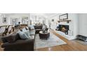 Open-concept living room with hardwood floors, a brick fireplace, and views into the modern white kitchen at 400 Edinburgh Dr, Cary, NC 27511